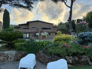 a house with two white chairs in a garden at Villa Valentina in Bracciano