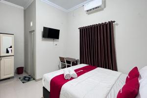 a hotel room with a bed and a tv at RedDoorz Syariah Omah Audrey near RSI Kota Magelang in Kedungsari