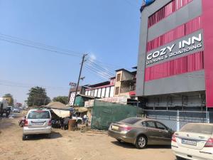 a group of cars parked in front of a building at Hotel Cozy Inn in Kālundri