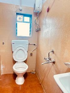 a bathroom with a toilet and a sink at Hotel Cozy Inn in Kālundri