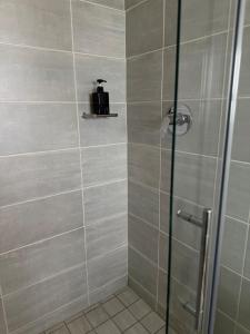 een douche met een glazen deur en een koffer op een plankje bij Zuri Marula Luxe in Midrand