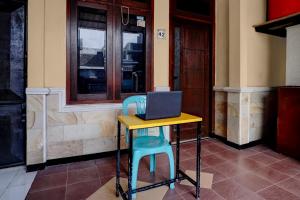 a desk and two chairs with a laptop on it at OYO 95035 Harmony Guest House Syariah Sawojajar in Ngadipuro
