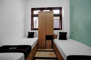 two beds in a small room with two windows at OYO 95035 Harmony Guest House Syariah Sawojajar in Ngadipuro