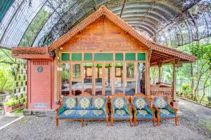 um pavilhão de madeira com cadeiras em uma estufa em OYO 95018 Anggrek Homestay Jogja Syariah em Timuran