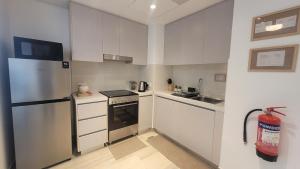 Una cocina con gabinetes blancos y un refrigerador de acero inoxidable. en Comfortable & Stylish, Steps from F1 Arena!, en Abu Dabi