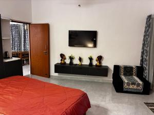a bedroom with a bed and a tv on a wall at Baidehi Cottage in Rishīkesh