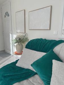 a green blanket sitting on a couch in a living room at Le cocon bleu, duplex cosy et lumineux in Précy-sur-Oise +8 photos