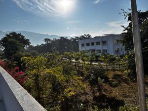 a white building with a fence and some bushes and trees at Baidehi Cottage in Rishīkesh