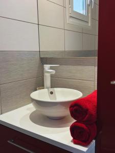a bathroom with a white sink and red towels at Le cocon bleu, duplex cosy et lumineux in Précy-sur-Oise