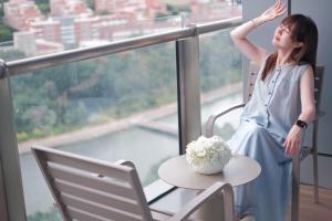泉州泉州东海假日酒店的一位女士坐在窗前的桌子旁。