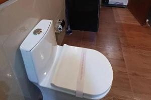 a bathroom with a white toilet with its lid down at Sacred Grove Homestay in Kalimpong