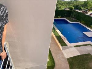 a person standing on a balcony next to a swimming pool at Apartment with pool in Culiacán