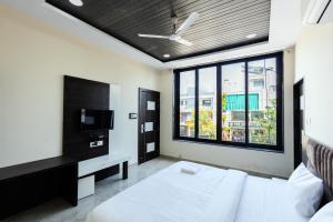 a bedroom with a white bed and a tv at Hotel Basil Inn in Ujjain
