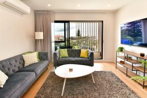 奥克兰Ocean View Retreat - Orewa Beach的客厅里有一张沙发和一张桌子。