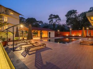 ein Innenhof mit Bänken und Sonnenschirmen und ein Pool in der Unterkunft The Hosteller Bam Coorg in Madikeri