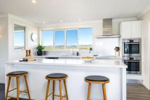 a kitchen with a large white island with three bar stools at Fairhall view 
