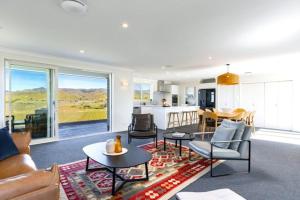 a living room with a couch and tables and a kitchen at Fairhall view 
