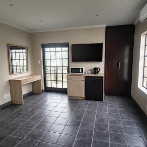 Una habitación vacía con una cocina con televisión y un mostrador. en Hippo Zwartkop Suites, en Centurion