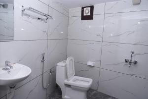 a white bathroom with a toilet and a sink at The Arena Edava in Paravūr +12 photos