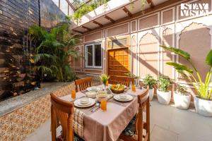 StayVista at Arches and Aura with Terrace, Meals في ماثورا: فناء مع طاولة وكراسي والنباتات