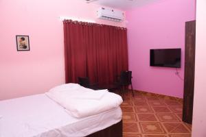 a bedroom with pink walls and a bed with a television at The Arena Edava in Paravūr