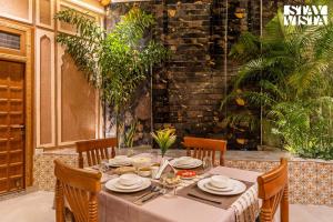 un tavolo con sedie e una tovaglia bianca. di StayVista at Arches and Aura with Terrace, Meals a Mathura
