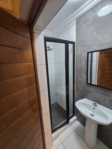 a bathroom with a sink and a glass shower door at La Majestic Guest Lodge in Centurion