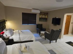 a hotel room with two beds and a tv at La Majestic Guest Lodge in Centurion