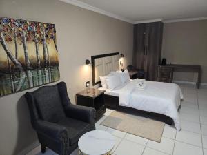 a hotel room with a bed and a chair at La Majestic Guest Lodge in Centurion