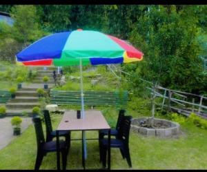 a table with a colorful umbrella in a garden at Aman magic resort in Takdāh
