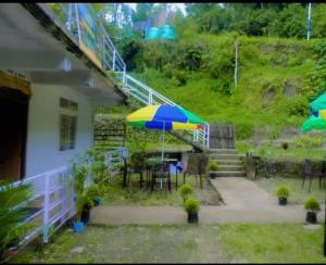 a patio with an umbrella and a table and chairs at Aman magic resort in Takdāh