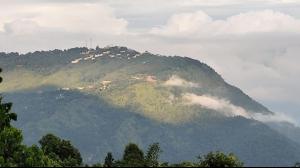 a mountain with a town on top of it at Aman magic resort in Takdāh +3 photos