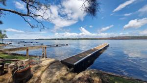 a dock on a lake with a bench in the water at Jerrinja - Absolute waterfront with jetty - 5 mins to Hyams Beach in Erowal Bay