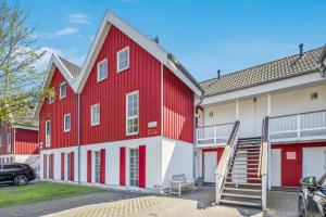 czerwono-biały budynek z samochodem zaparkowanym przed budynkiem w obiekcie Seestern Greetsiel für bis zu 4 Personen - Haustiere herzlich willkommen, direkt am Hafen, Whirlpool, Kaminofen w mieście Greetsiel