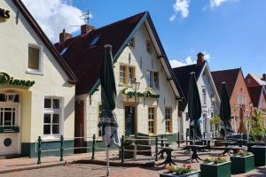 特希尔Skipper Asterix Greetsiel für max. 4 Personen - Haustiere herzlich willkommen, direkt am Hafen的街道上带桌子和遮阳伞的建筑