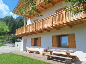 a house with a wooden balcony and a picnic table at Cesa de Conesel in Colle Santa Lucia