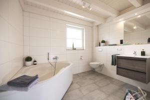 诺德霍恩Haus Norwald - tolles Ferienhaus direkt am See für bis zu 4 Personen mit Sauna und Kaminofen - Haustiere herzlich willkommen的带浴缸和马桶的白色浴室 更多21张照片