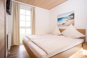 a bedroom with a bed with a large window at Seemannsgarn Greetsiel - tolle Erdgeschosswohnung mit Kaminofen für bis zu 4 Personen - Haustiere herzlich willkommen in Greetsiel