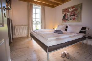 特希尔Hellinghus Greetsiel - mit Sauna, Whirlpool und Kaminofen für bis zu 6 Personen - Haustiere herzlich willkommen, direkt am Hafen von Greetsiel的地板上带鞋的房间的一张大床