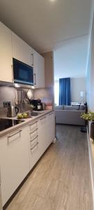 a kitchen with white cabinets and a wooden floor at PiMa aan Zee Julianadorp - charmantes Appartement für bis zu 2 Personen in unmittelbarer Nähe zum Strand - Haustiere herzlich willkommen in Julianadorp