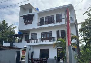 a white building with balconies and a palm tree at Eros Green House in Unawatuna