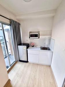 een kleine keuken met een spoelbak en een koelkast bij Plum condo Bang-yai station in Nonthaburi