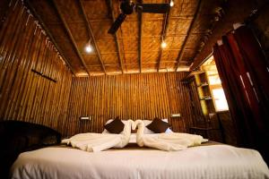 ein Schlafzimmer mit einem Bett mit weißen Laken und Kissen in der Unterkunft Dandeli Dreams in Kurandi