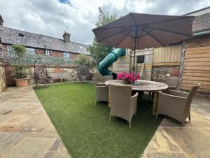 a patio with a table with an umbrella and a playground at The barn Alexandra mews in Heathfield