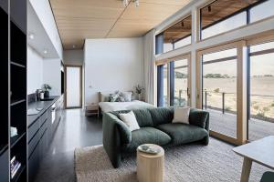 a bedroom with a green couch and a bed with a view at Studio on Forktree – Modern Coastal Retreat in Carrickalinga +4 photos