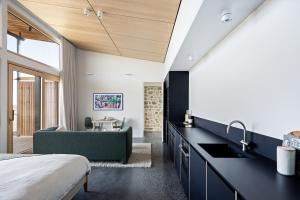 a bedroom with a bed and a kitchen with a sink at Studio on Forktree – Modern Coastal Retreat in Carrickalinga