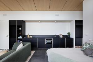 a living room with a bed and a kitchen at Studio on Forktree – Modern Coastal Retreat in Carrickalinga