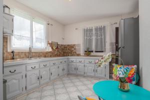 Maison Vue du Ciel - Proche de l'aéroport في ليه أبيم: مطبخ بدولاب بيضاء وطاولة زرقاء