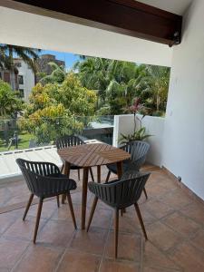 a wooden table and chairs on a patio with a view of trees at Lakaz Mapou - Magnifiques Appartements rénovés de 3 chambres et 2 salles de bains in Rivière Noire