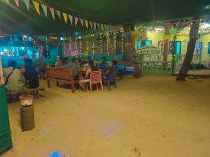 Oceanview Nohas Guesthouse Arambol في أرامبول: مجموعة من الناس يجلسون على طاولة تحت خيمة